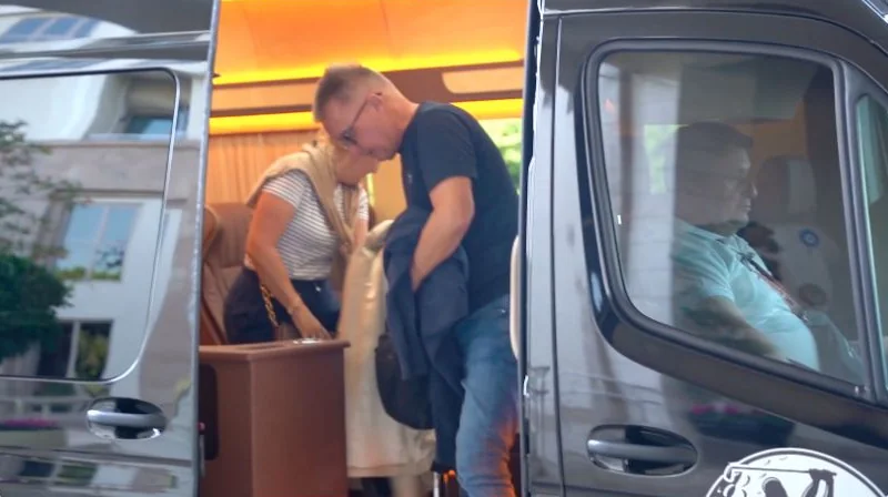Guests beside an Alexa Golf transfer minibus with its passenger door open and seating visible inside
